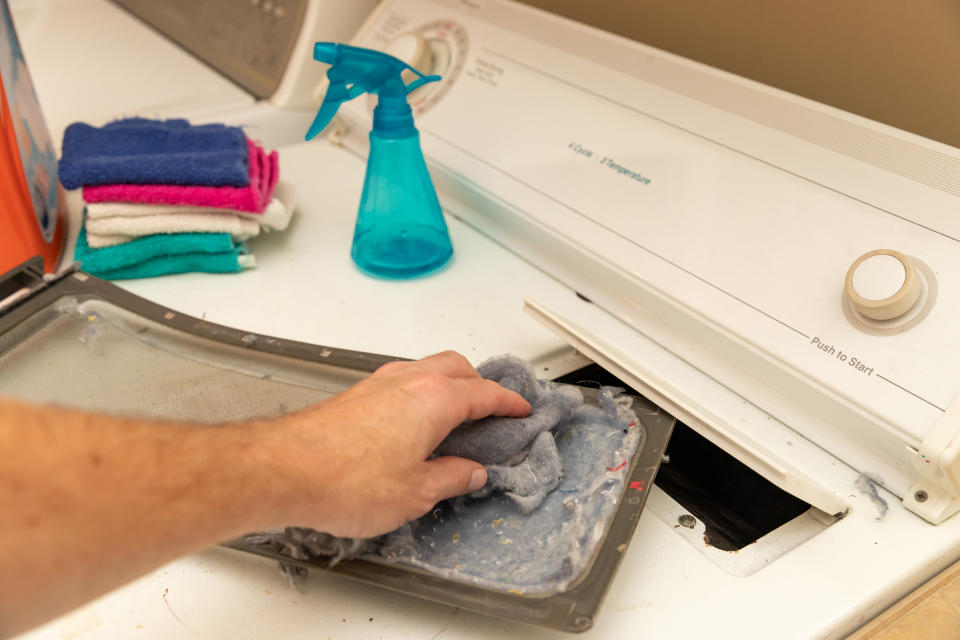 hand removing dirty lint screen of dryer while doing laundry