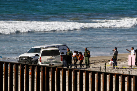 U.S. border patrol accompany Honduran migrants who turned themselves in after entering the U.S. through the border fence between Mexico and the United States, as seen from Tijuana, Mexico November 14, 2018. REUTERS/Jorge Duenes