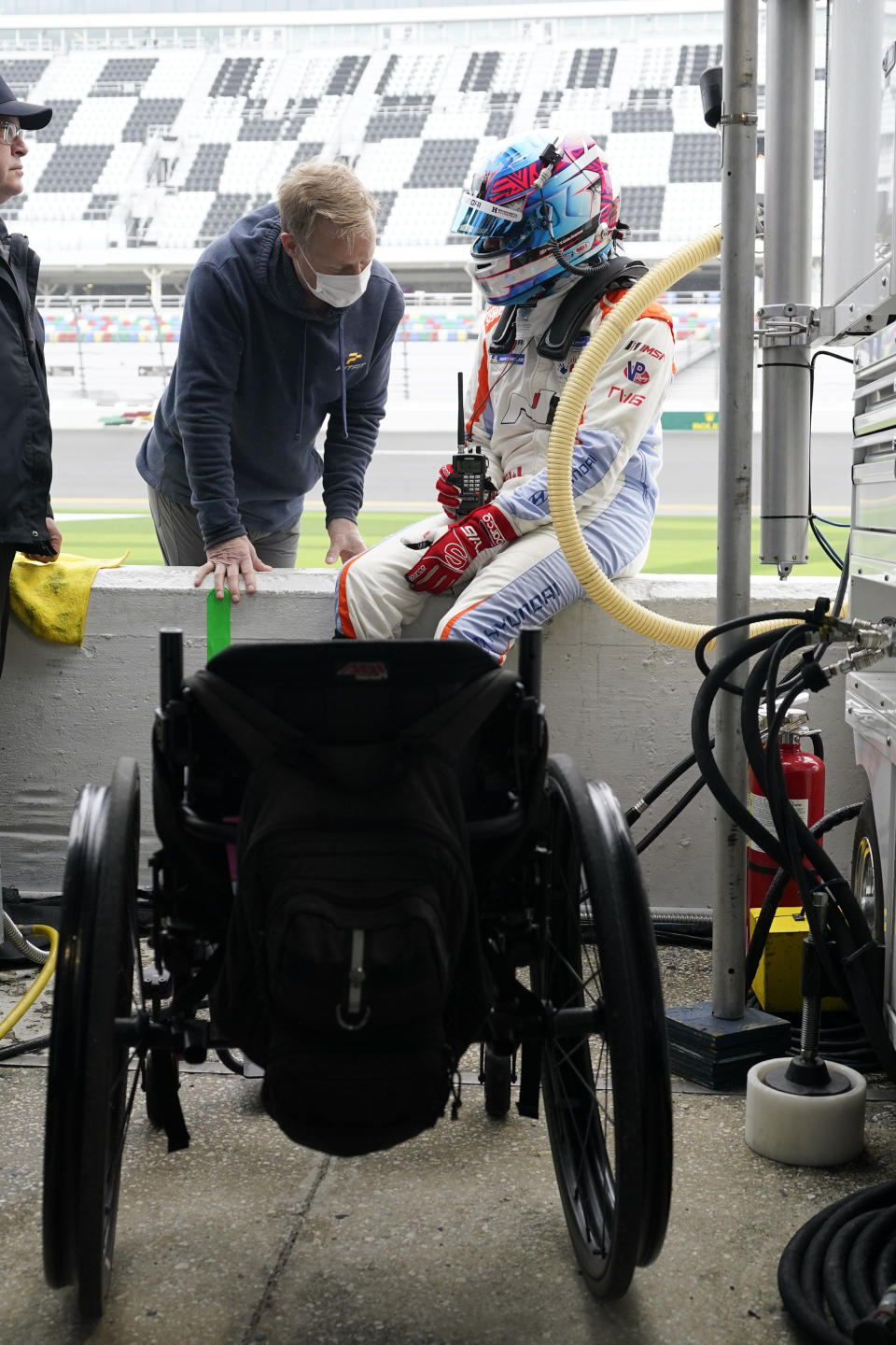 FILE - Robert Wickens, right, talks with physical trainer Jim Leo before taking a turn driving during practice for the Rolex 24 hour auto race at Daytona International Speedway, Thursday, Jan. 27, 2022, in Daytona Beach, Fla. Wickens used hand controls last weekend to win his first race since a 2018 spinal cord injury temporarily ended his racing career. Across an ocean, former IndyCar driver Sam Schmidt and motorcycle racer Wayne Rainey also piloted vehicles during the annual Goodwood Festival of Speed in England. (AP Photo/John Raoux, File)