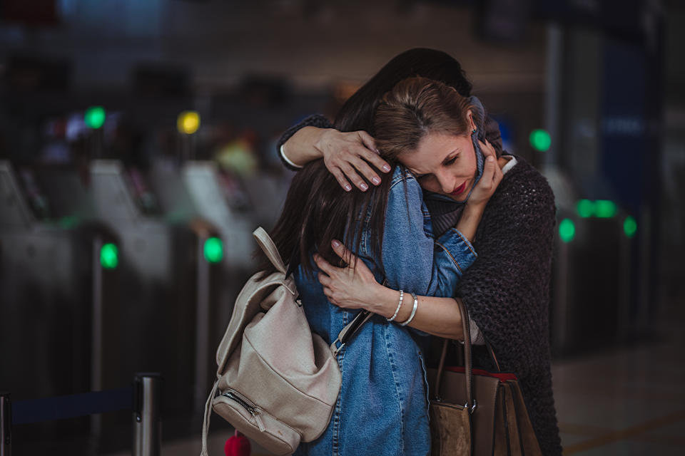 Two women embracing warmly in an airport setting, conveying a sense of emotional reunion