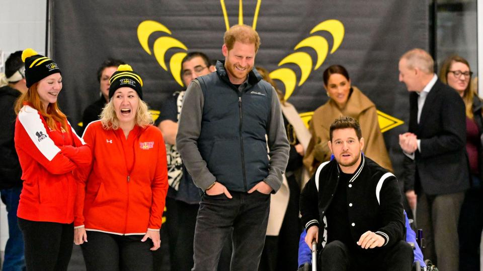 Prince Harry smiles as Michael Buble tries 