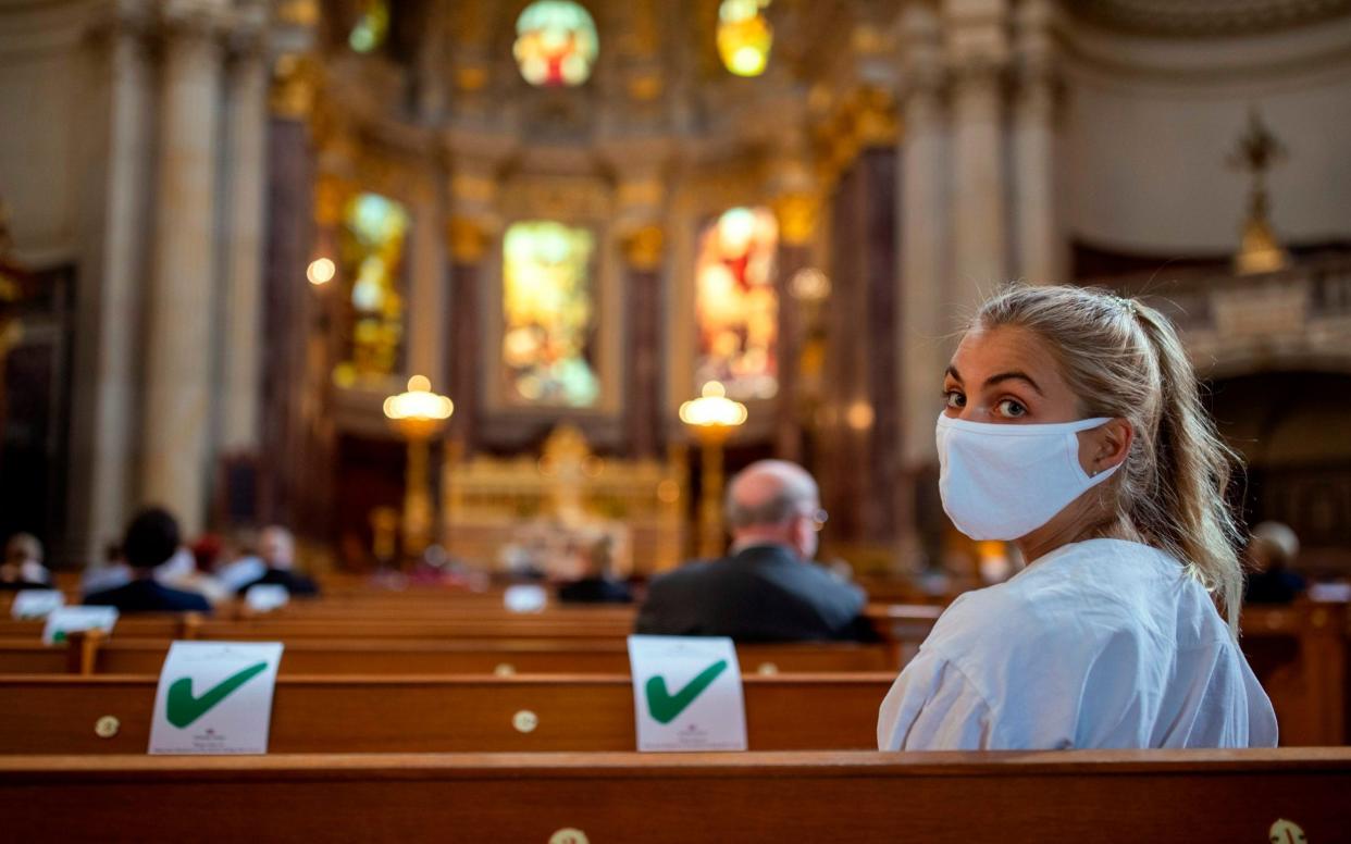 A woman wearing a protective face mask attends a Sunday service at the Berliner Dom cathedral in Berlin  - AFP