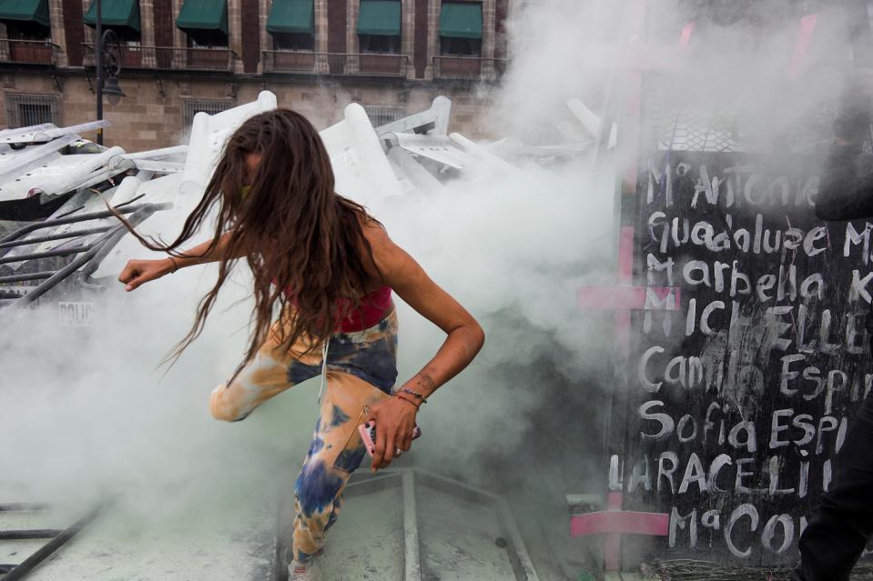 A woman runs through tear gas during a protest outside the National PalaceREUTERS