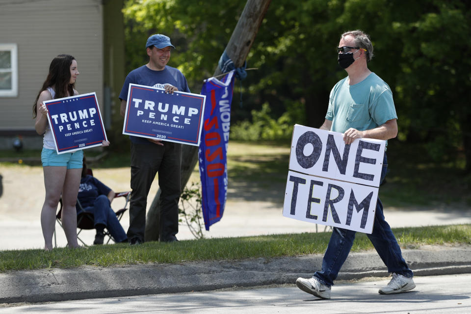 A man walks past supporters of President Donald Trump prior to the arrival of the president, Friday, June 5, 2020, in Guilford, Maine. Trump is scheduled to visit Puritan Medical Products Co., one of the top two makers of testing swabs in the world. (AP Photo/Robert F. Bukaty)