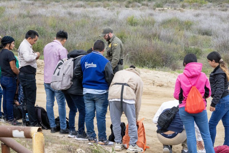 Migrants surrender to the U.S. Border Patrol after crossing the border wall from Mexico near Campo, Calif., on Wednesday. Catholic bishops are worried about threats to strip religious charities of public funding to provide humanitarian aid to immigrants. Photo by Pat Benic/UPI