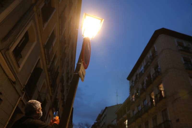 A passerby records Spanish blues singer "Betta" singing from her balcony during a daily evening concert to support health workers and to make it easier for her neighbours to bear the coronavirus lockdown in Madrid