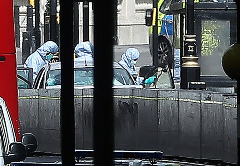 Police forensics officers inspect the car that crashed into a barrier outside Parliament in London