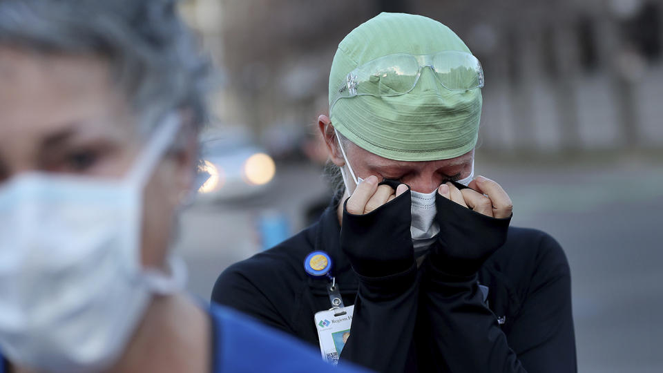 Healthcare workers at Regions Hospital, including Tamara Hill, an ER nurse, seen wiping away tears, come outside to thank Xcel Energy crew members who had lined the street outside Regions to greet healthcare workers Wednesday, April 22, 2020, in St. Paul, Minn., during the coronavirus outbreak. (David Joles/Star Tribune via AP)