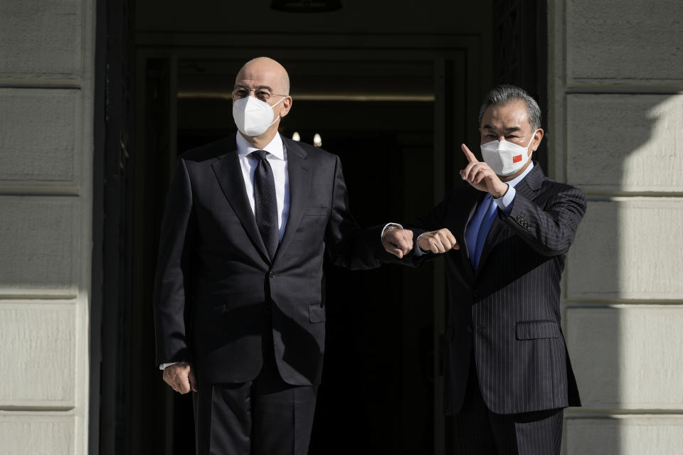 Greece's Foreign Minister Nikos Dendias, left, welcomes his Chinese counterpart Wang Yi prior their meeting, in Athens, on Wednesday, Oct. 27, 2021. (AP Photo/Petros Giannakouris)