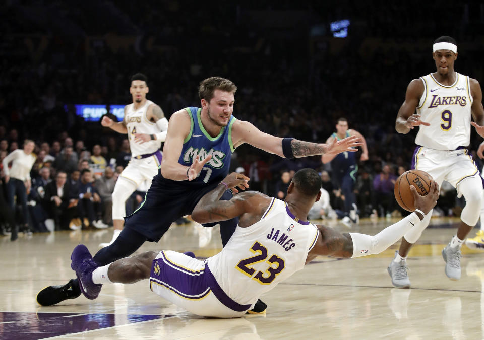 Los Angeles Lakers' LeBron James (23) recovers a loose ball under Dallas Mavericks' Luka Doncic (77) during the first half of an NBA basketball game Sunday, Dec. 1, 2019, in Los Angeles. (AP Photo/Marcio Jose Sanchez)