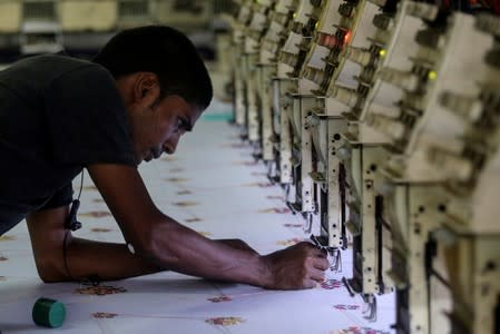 A worker adjusts the thread on an embroidery machine at a workshop in Mumbai