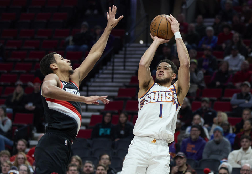 Phoenix Suns guard Devin Booker, right, looks to shoot over Portland Trail Blazers forward Kris Murray, left, during the first half of an NBA basketball game in Portland, Ore., Sunday, Jan. 14, 2024. (AP Photo/Craig Mitchelldyer)