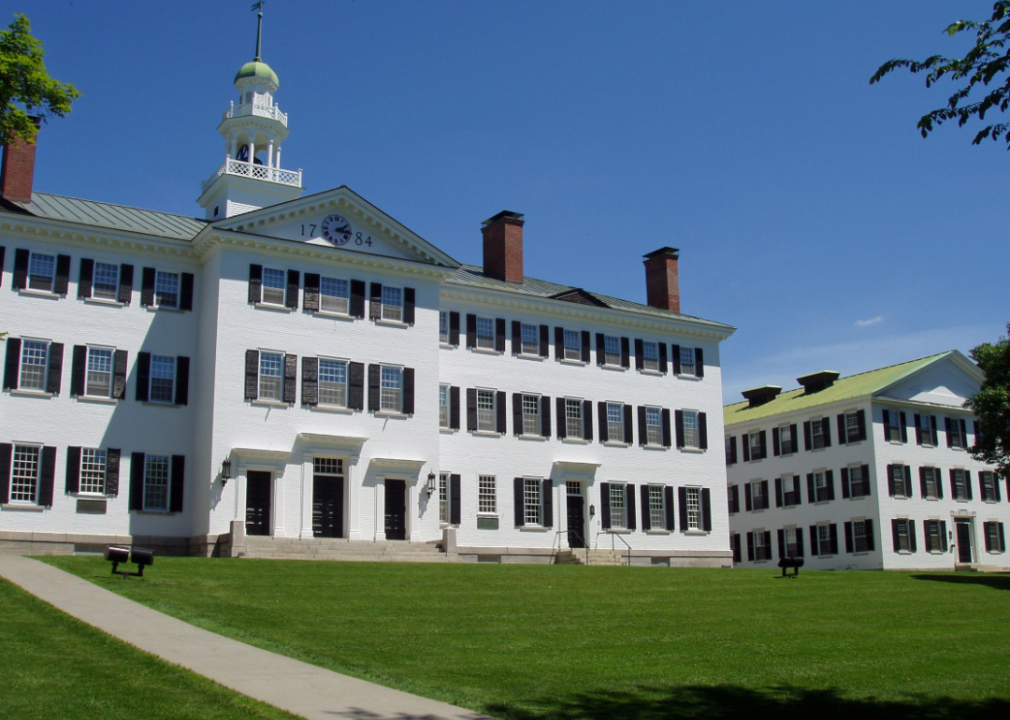 Two white buildings with black shutters and a green lawn.