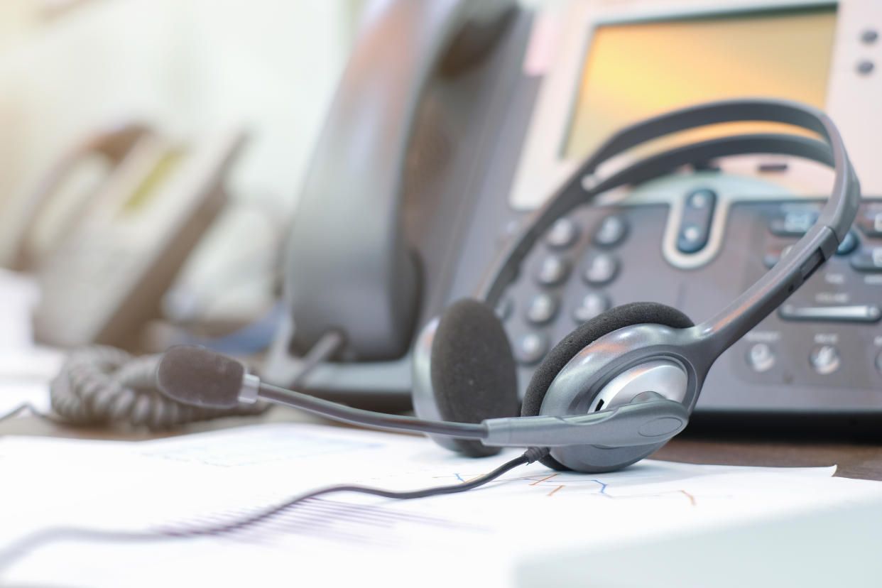 close up focus on call center headset device at telephone VOIP system at office desk for hotline telemarketing concept