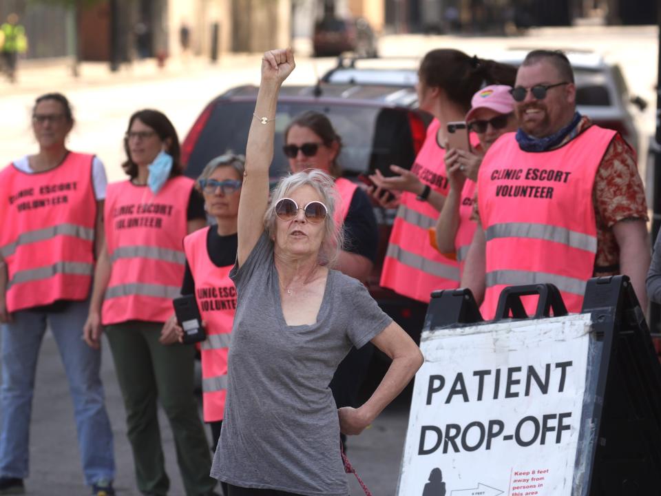 abortion clinic escort volunteers in pink vests with woman with fist in air