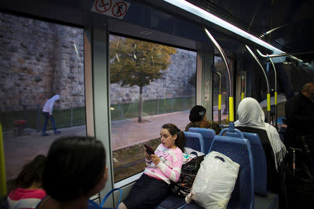 FILE PHOTO: A girl uses a mobile phone as she rides a light rail tram in Jerusalem November 11, 2014. REUTERS/Ronen Zvulun/File Photo