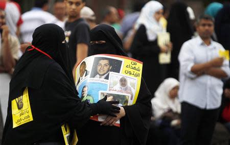 A member of the Muslim Brotherhood and supporter of ousted Egyptian President Mohamed Mursi passes a poster to another during a protest named "People Protect the Revolution" as they march towards the "Qasr al-Quba" presidential palace in Cairo, September 6, 2013. Egypt's army-backed authorities have decided to annul the Muslim Brotherhood's non-governmental organisation, an official said on Friday, widening a drive to neutralise the movement behind Mursi. REUTERS/Amr Abdallah Dalsh