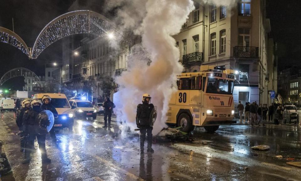 Riot police officers stand on a main boulevard in Brussels at night