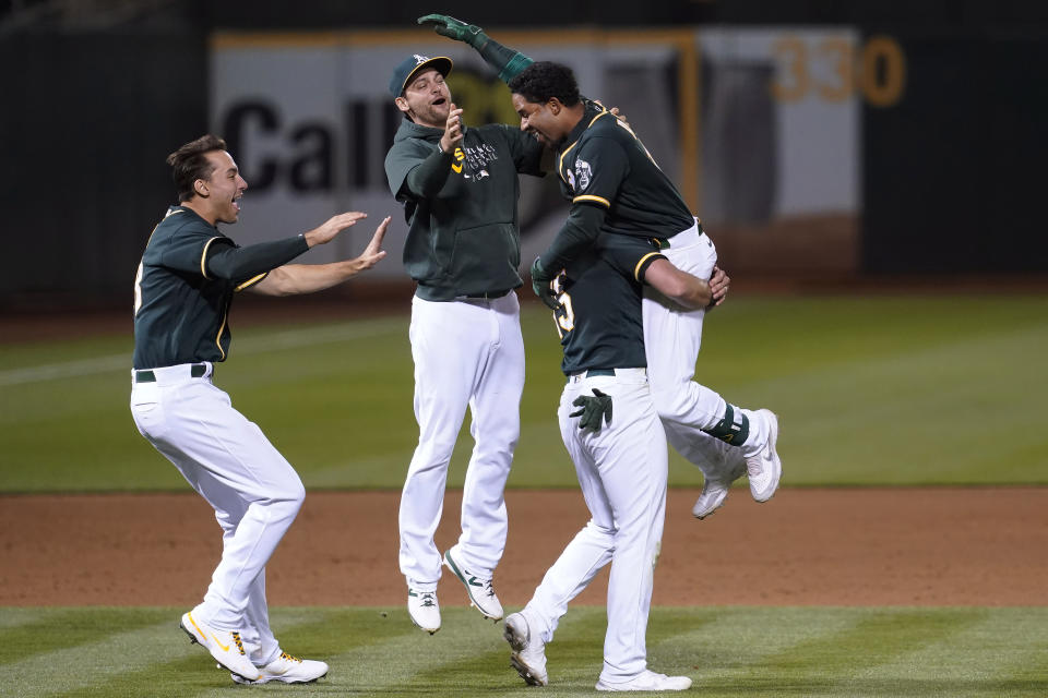 Oakland Athletics' Elvis Andrus, top right, is congratulated by teammates after hitting a single to score Matt Chapman during the ninth inning of a baseball game against the Kansas City Royals in Oakland, Calif., Friday, June 11, 2021. (AP Photo/Jeff Chiu)