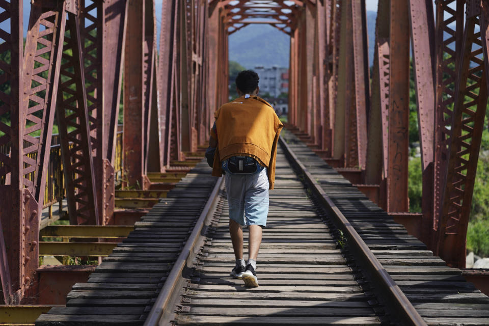 A man who is part of a migrant caravan walks on the tracks of a railroad in Huixtla, Chiapas state, Mexico, Tuesday, Oct. 26, 2021, on a day of rest before continuing their trek across southern Mexico to the U.S. border. (AP Photo/Marco Ugarte)