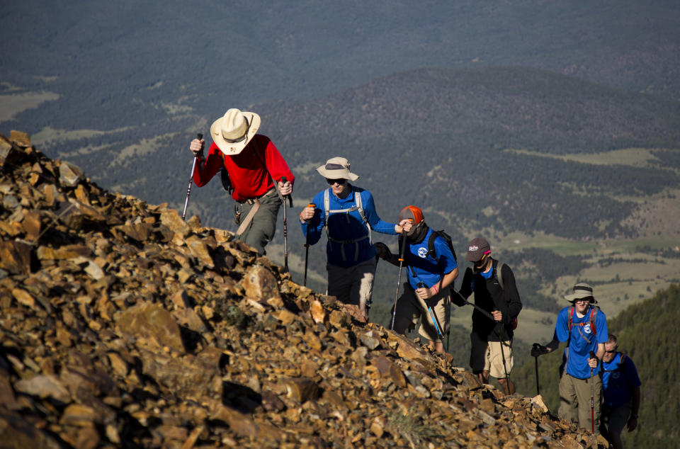 In this July 18, 2017, photo provided by the Philmont Scout Ranch, a crew hikes up Baldy Mountain, the tallest peak on the ranch near Cimarron, New Mexico. Philmont is rebuilding following a devastating wildfire that burned nearly 44 square miles in 2018. Backcountry trails were wiped out along with trail camps. (Hunter Long/Philmont Scout Ranch via AP)