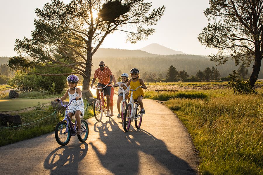 a family goes biking in a golden sunset at the sunriver resort, a good housekeeping pick for best family vacation destinations