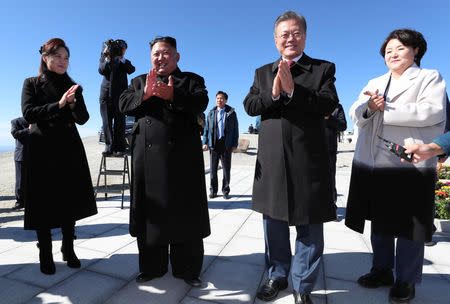 South Korean President Moon Jae-in and North Korean leader Kim Jong Un react as they arrive at the top of Mt. Paektu, North Korea, September 20, 2018. Pyeongyang Press Corps/Pool via REUTERS