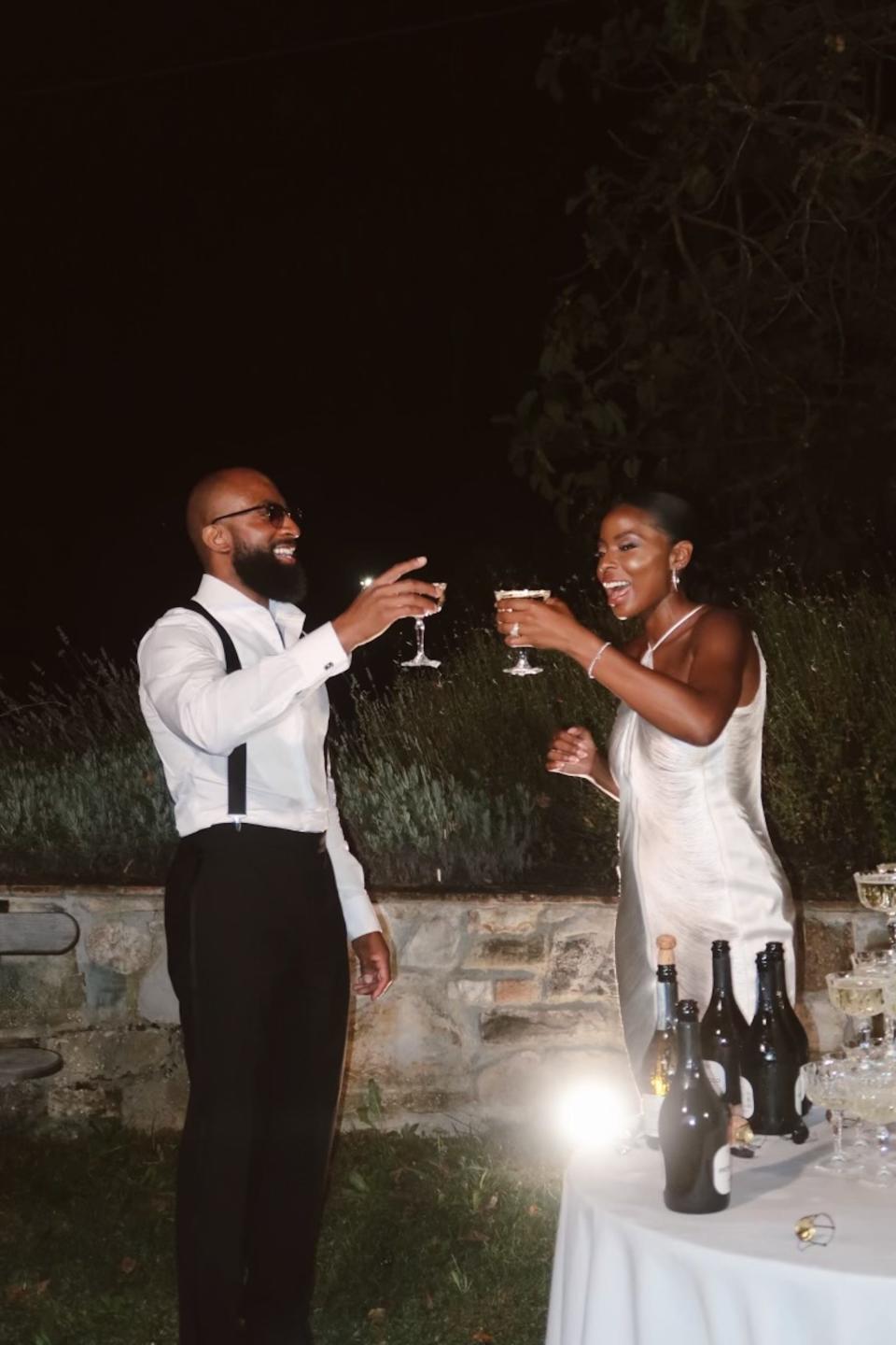 A bride and groom raise their glasses to each other at their wedding.