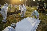 FILE - In this April 25, 2021, file photo, municipal workers prepare to bury a person who died of COVID-19 in Gauhati, India. Despite clear signs that India was being swamped by another surge of coronavirus infections, Prime Minister Narendra Modi refused to cancel campaign rallies, a major Hindu festival and cricket matches with spectators. The crisis has badly dented Modi’s carefully cultivated image as an able technocrat. (AP Photo/Anupam Nath, File)