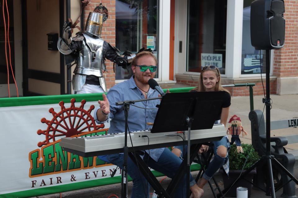 David Garcia of Adrian, dressed in a suit of armor, dances while Lucas Vanzandt of Tipton performs and Katlin Wilkinson of Jackson watches Sept. 18, 2021, during the Artalicious Fine Arts Fair in downtown Adrian.