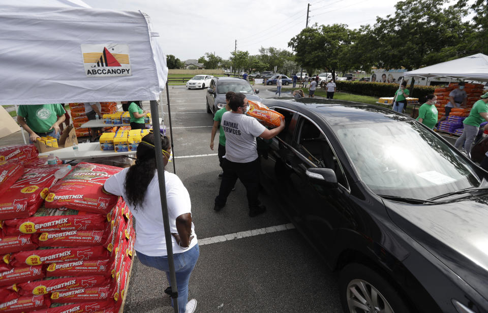 Employees and volunteers at a Miami-Dade County Animal Services Department Drive-Thru Pet Food Bank load pet food into cars at Lake Stevens Park, Thursday, June 4, 2020, in Miami Gardens, Fla. About 40,000 lbs of dog and cat food donated by the American Society for the Prevention of Cruelty to Animals as part of their national ASPCA COVID-19 Relief & Recovery Initiative were distributed Thursday. (AP Photo/Wilfredo Lee)