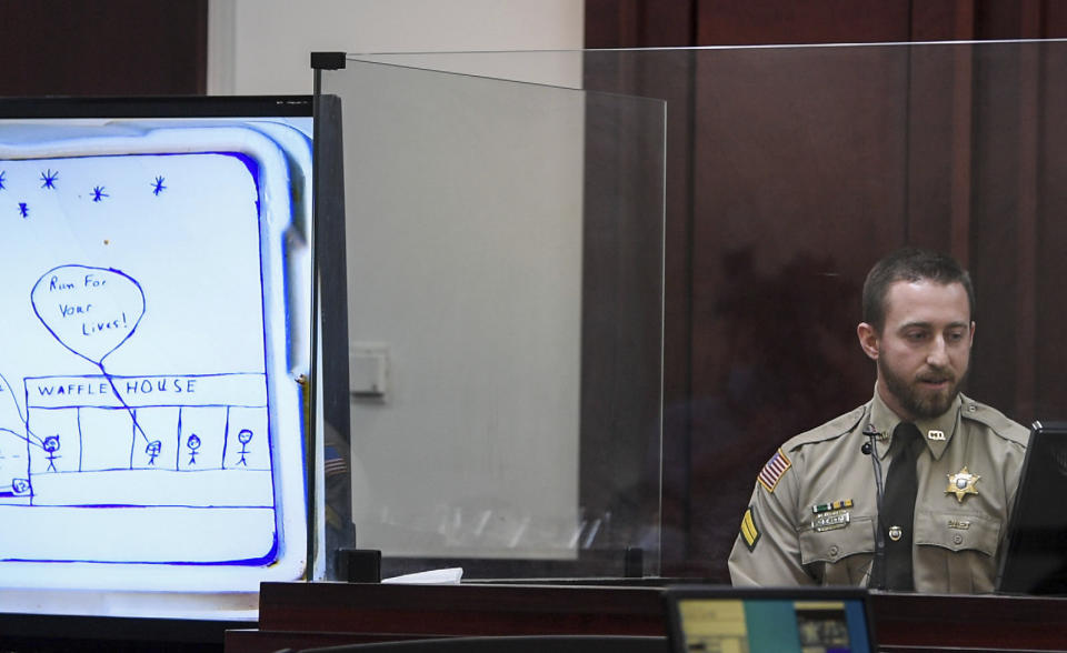 Davidson County County Sherriff's office Corporal Jacob Bianchi looks at the food container with a drawling on it, by Travis Reinking, showing the Waffle House shooting, one year after the actual incident, in court at Justice A.A. Birch Building in Nashville, Tenn., Thursday, Feb. 3, 2022. (Stephanie Amador/The Tennessean via AP, Pool)