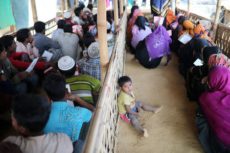 A Rohingya child sits on the floor while his mother waits in a queue to collect aid supplies in Kutupalong refugee camp in Cox's Bazar, Bangladesh, January 21, 2018. REUTERS/Mohammad Ponir Hossain