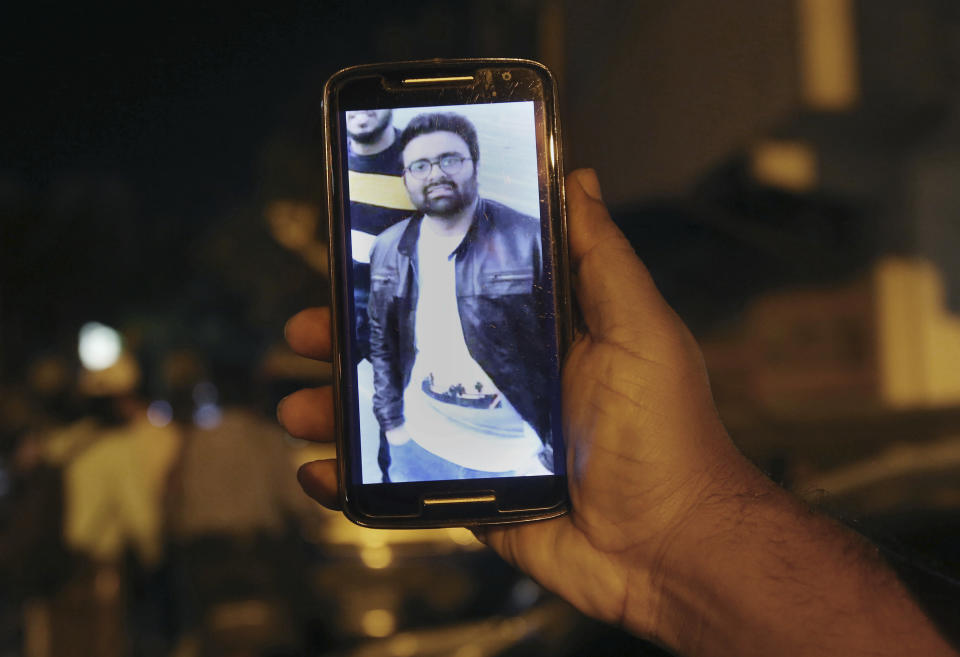 A relative shows the picture of Syed Areeb Ahmed, a Pakistani citizen who was killed the Christchurch mosque shooting, on his cell phone outside his home in Karachi, Pakistan, Saturday, March 16, 2019. Pakistan's foreign minister says at least six Pakistanis were killed in the New Zealand mosque shootings. Shah Mahmood Qureshi says authorities in Christchurch, where the shootings took place, are trying to determine whether three other Pakistanis who have been missing since Friday's attack were among the fatalities. (AP Photo/Fareed Khan)