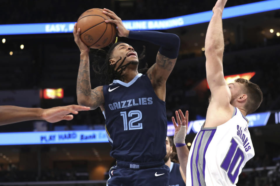 Sacramento Kings guard Ja Morant (12) shoots defended by Sacramento Kings forward Domantas Sabonis (10) In the first half of an NBA basketball game, Sunday, Jan. 1, 2023, in Memphis, Tenn. (AP Photo/Nikki Boertman)