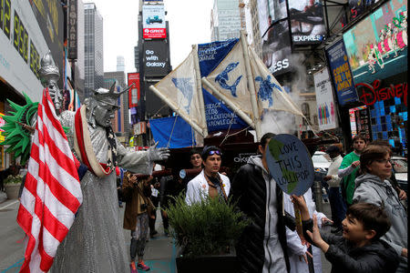 A person in costume as the Statue of Liberty watches people walk through Times Square during the Earth Day 'March For Science NYC' demonstration to coincide with similar marches globally in Manhattan, New York, U.S., April 22, 2017. REUTERS/Andrew Kelly