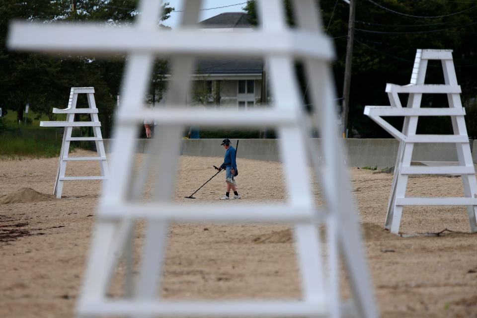 A man scans East Beach in New Bedford for treasure as seen through the lifeguard stands.