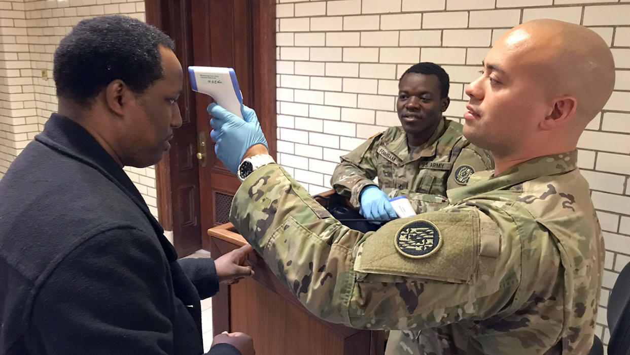 Journalist William J. Ford of The Washington Informer has his temperature read by Sgt. Jason Grant, right, of the Maryland National Guard as PFC Theophilus Foinmbam looks on Thursday, March 19, 2020 at the State House in Annapolis. Everyone entering the State House must go through a temperature screening, answer health questions, and provide a phone number. (Amy Davis./The Baltimore Sun via AP)