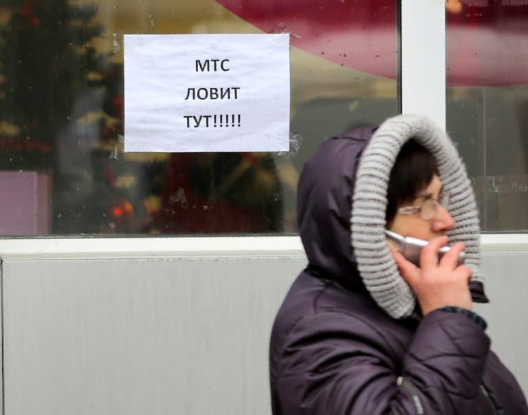 A caller tries to catch a signal from cell phone towers by a sign reading "MTS is available here" in one of the few places available for mobile connection provided by Vodafone Ukraine (former MTS) in Donetsk