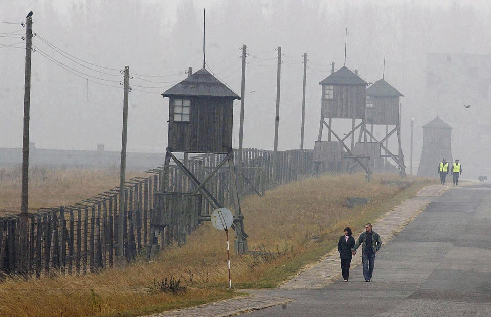 FILE - In this Nov. 9, 2005 file photo, a couple is seen walking along the outer fence of the former Nazi death camp Majdanek outside Lublin in eastern Poland. A police spokesman in eastern Poland says an Israeli teen has admitted to dropping his pants at the former Nazi German death camp of Majdanek and is facing a fine. Andrzej Fijolek said Monday, Aug. 13, 2018 the 17-year-old, whose identity has not been released, was caught on CCTV cameras as he let down his pants by one of the wooden barracks at the Majdanek museum while on a school trip there Friday. (AP Photo/Czarek Sokolowski)