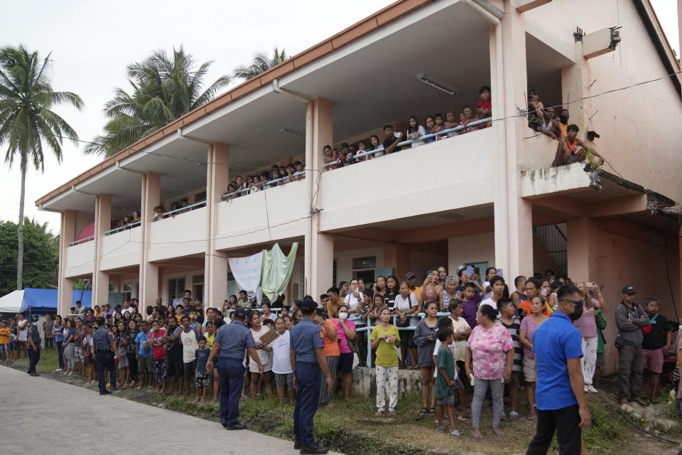 Evacuees watch from a building to catch a glimpse of Philippine President Ferdinand Marcos Jr. as he visited an evacuation center in Guinobatan town, Albay province, northeastern Philippines, Wednesday, June 14, 2023. A gentle eruption of the Philippines' most active volcano that has forced nearly 18,000 people to flee to emergency shelters could last for months and create a protracted crisis, officials said Wednesday. (AP Photo/Aaron Favila)