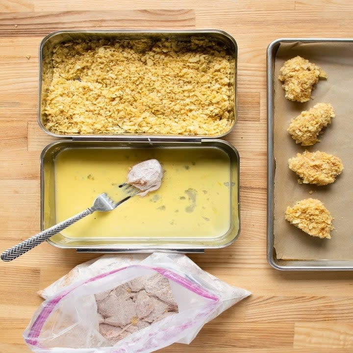 Dredging chicken nuggets into egg and potato chip bread crumbs