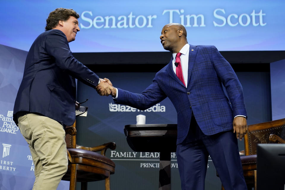 Republican presidential candidate Sen. Tim Scott, R-S.C., greets moderator Tucker Carlson, left, during the Family Leadership Summit, Friday, July 14, 2023, in Des Moines, Iowa. (AP Photo/Charlie Neibergall)