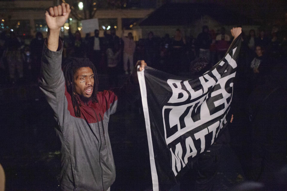 Protesters carrying a Black Lives Matter flag march inside a fountain at Veterans Memorial Park following a march from the Grand Rapids Police Department. The protest was held in response to videos of the shooting of Patrick Lyoya, by a Grand Rapids police officer from April 4, being released to the public on Wednesday, April 13, 2020, in Grand Rapids, Mich. (Daniel Shular/The Grand Rapids Press via AP)