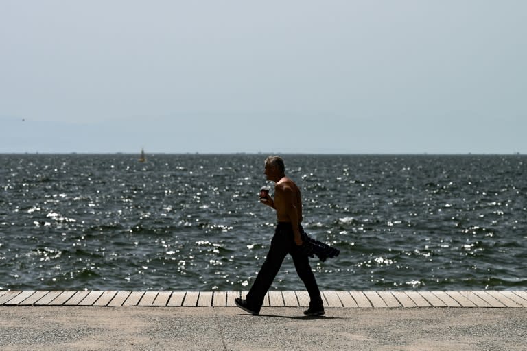 Un hombre camina sin camiseta al borde del mar en la ciudad griega de Salónica el 12 de junio de 2024 (Sakis Mitrolidis)