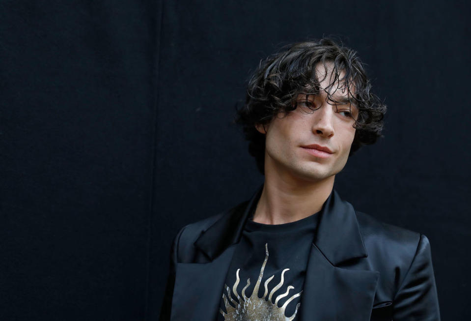 A close-up of Ezra slightly smiling while wearing a t-shirt and a blazer
