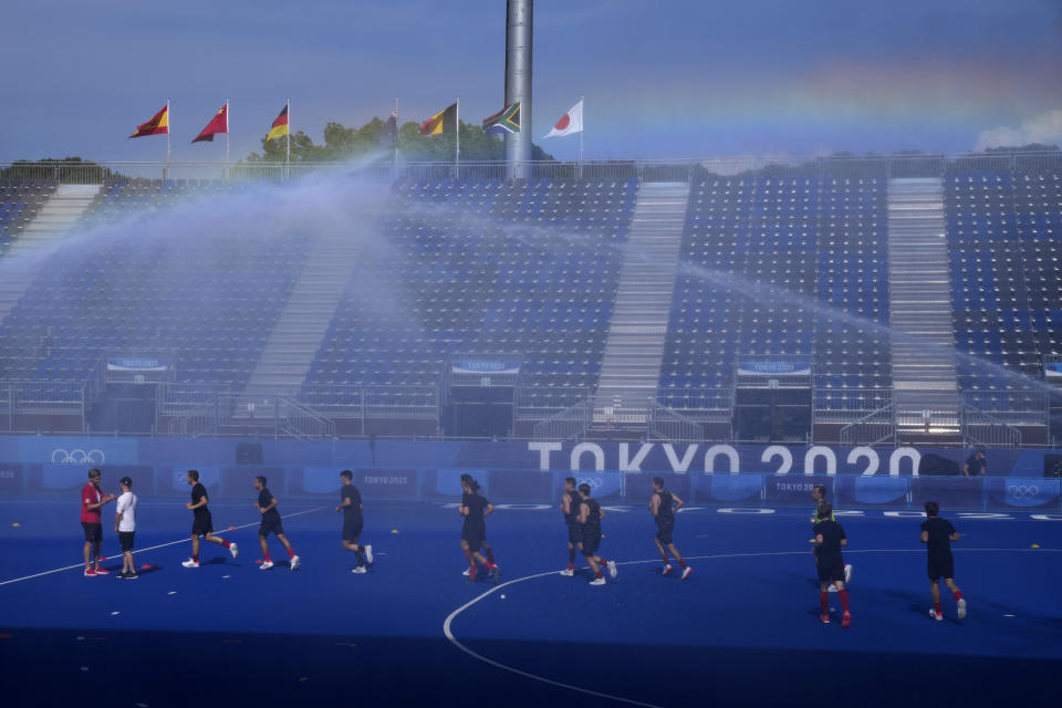 Members of the Canadian men's field hockey team run beneath sprinklers during a training session at Oi Hockey Stadium ahead of the the 2020 Summer Olympics, Thursday, July 22, 2021, in Tokyo, Japan. (AP Photo/John Locher)