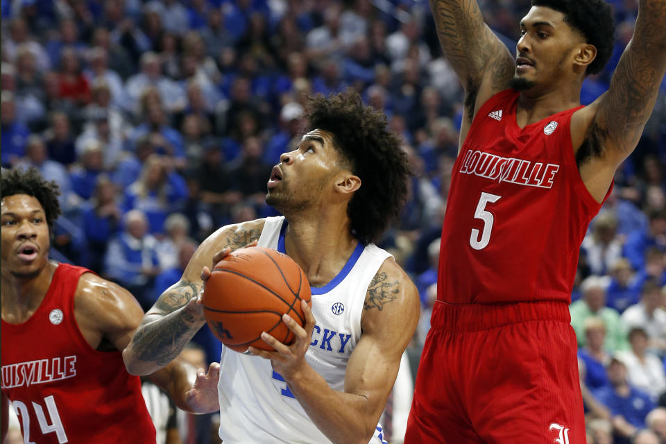 Kentucky's Nick Richards, middle, shoots between Louisville's Dwayne Sutton (24) and Malik Williams (5) during the first half of an NCAA college basketball game in Lexington, Ky., Saturday, Dec. 28, 2019. (AP Photo/James Crisp)
