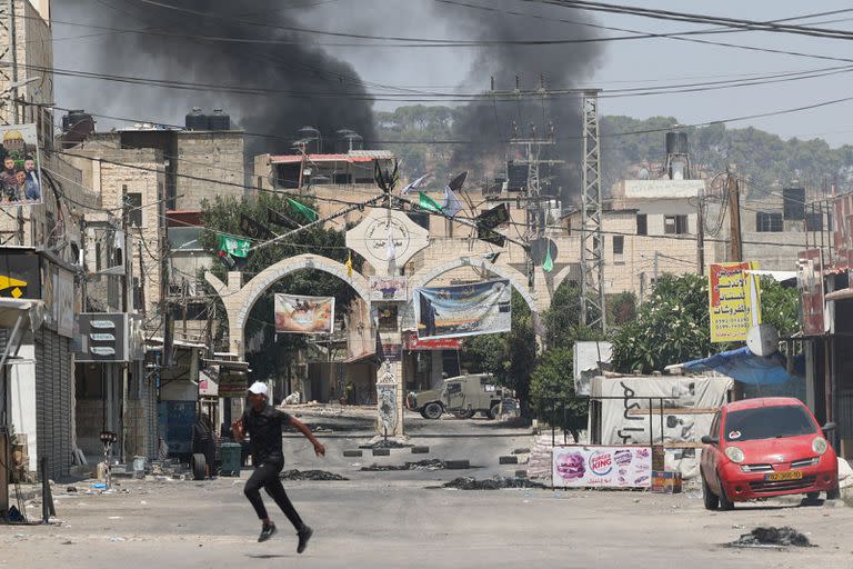 Jóvenes palestinos corren en busca de refugio en medio de enfrentamientos durante una operación militar israelí en la ciudad de Yenín en Cisjordania ocupada, el 3 de julio de 2023. 