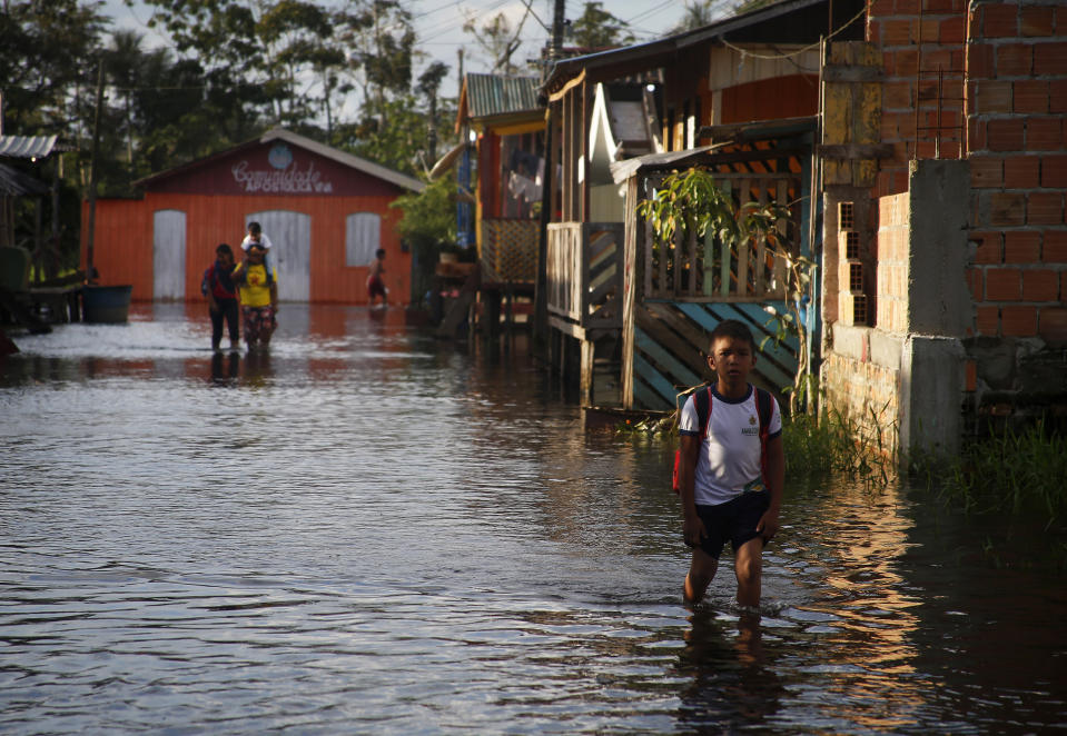 A student walks to school on a street flooded by the rise of the Negro river in Iranduba, Amazonas state, Brazil, Monday, May 23, 2022. The Amazon region is being hit hard by flooding with 35 municipalities that are facing one of their worst floods in years and the water level is expected to rise over the coming months. (AP Photo/Edmar Barros)